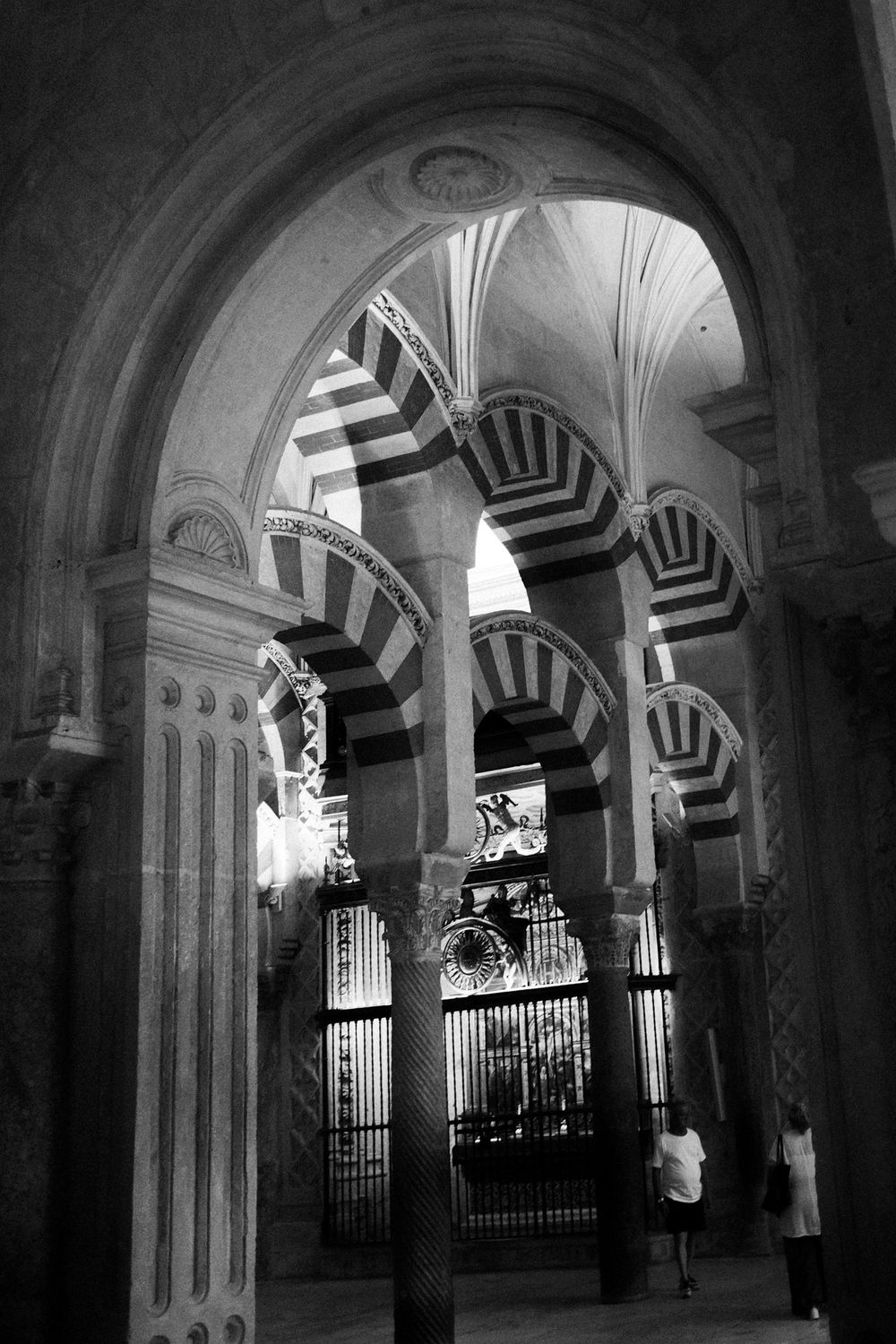 Interior of Mezquita-Catedral de Córdoba featuring iconic red and white striped arches and ornate columns.