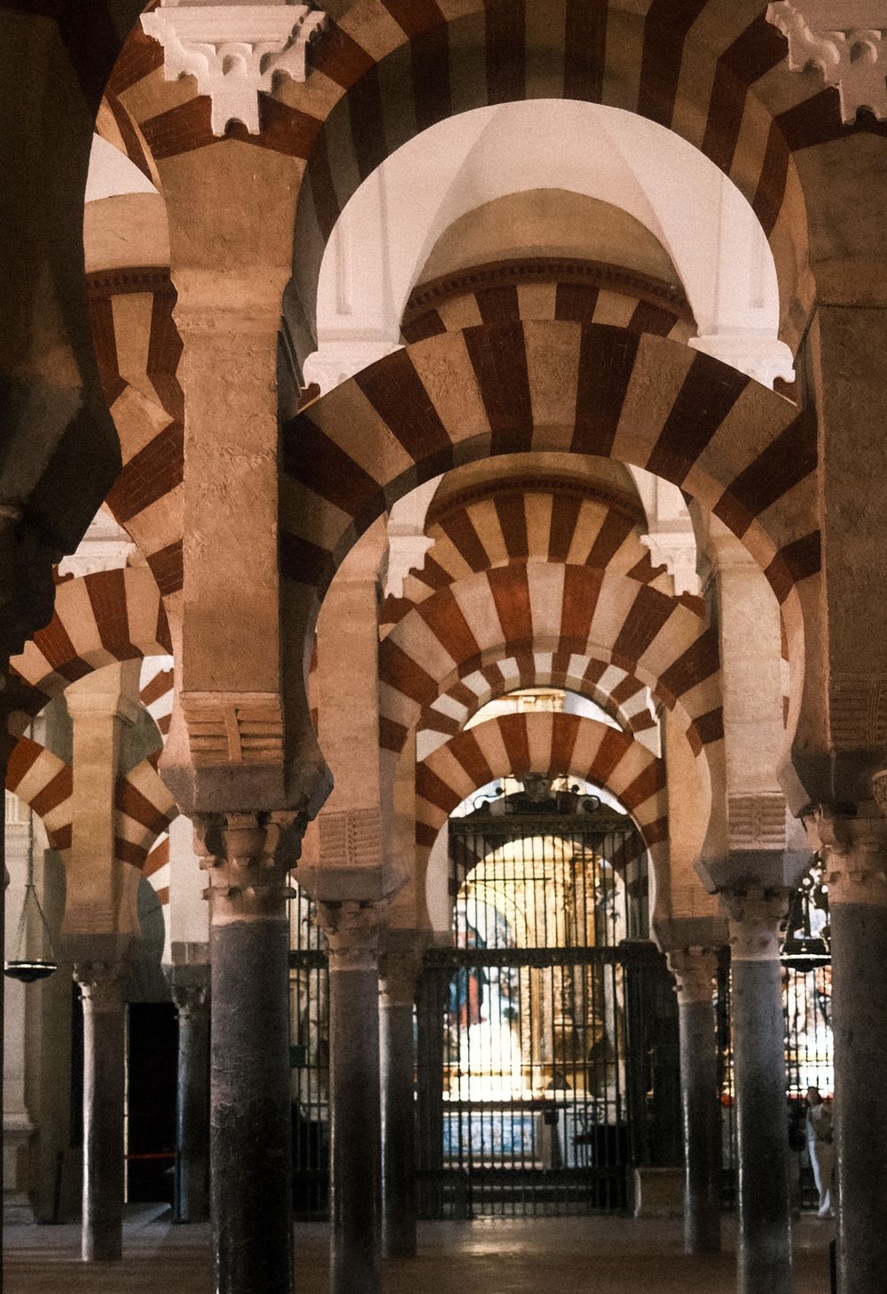 Interior of Mezquita-Catedral de Córdoba featuring iconic red and white striped arches and ornate columns.