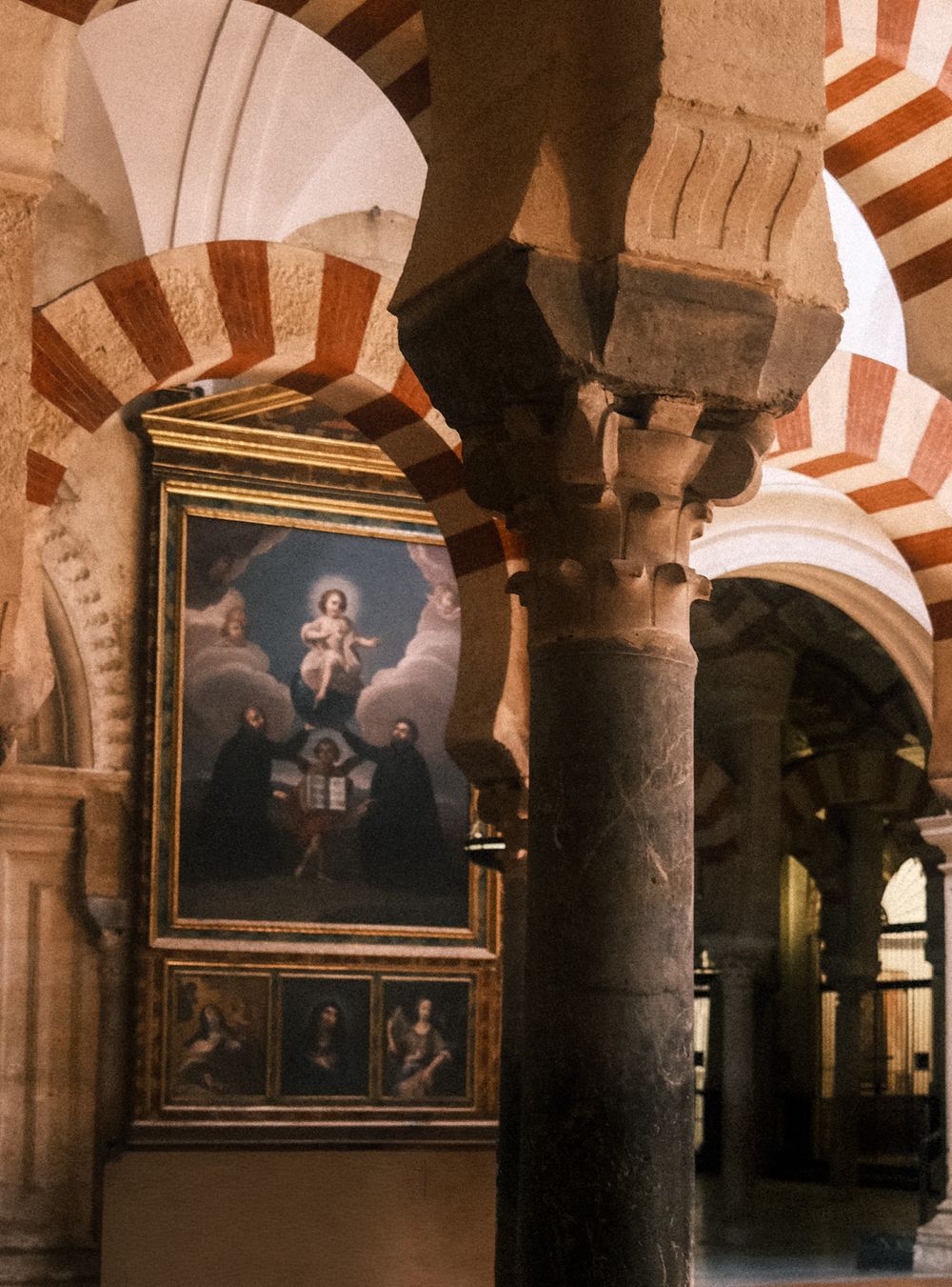 Interior of Mezquita-Catedral de Córdoba featuring iconic red and white striped arches and ornate columns.