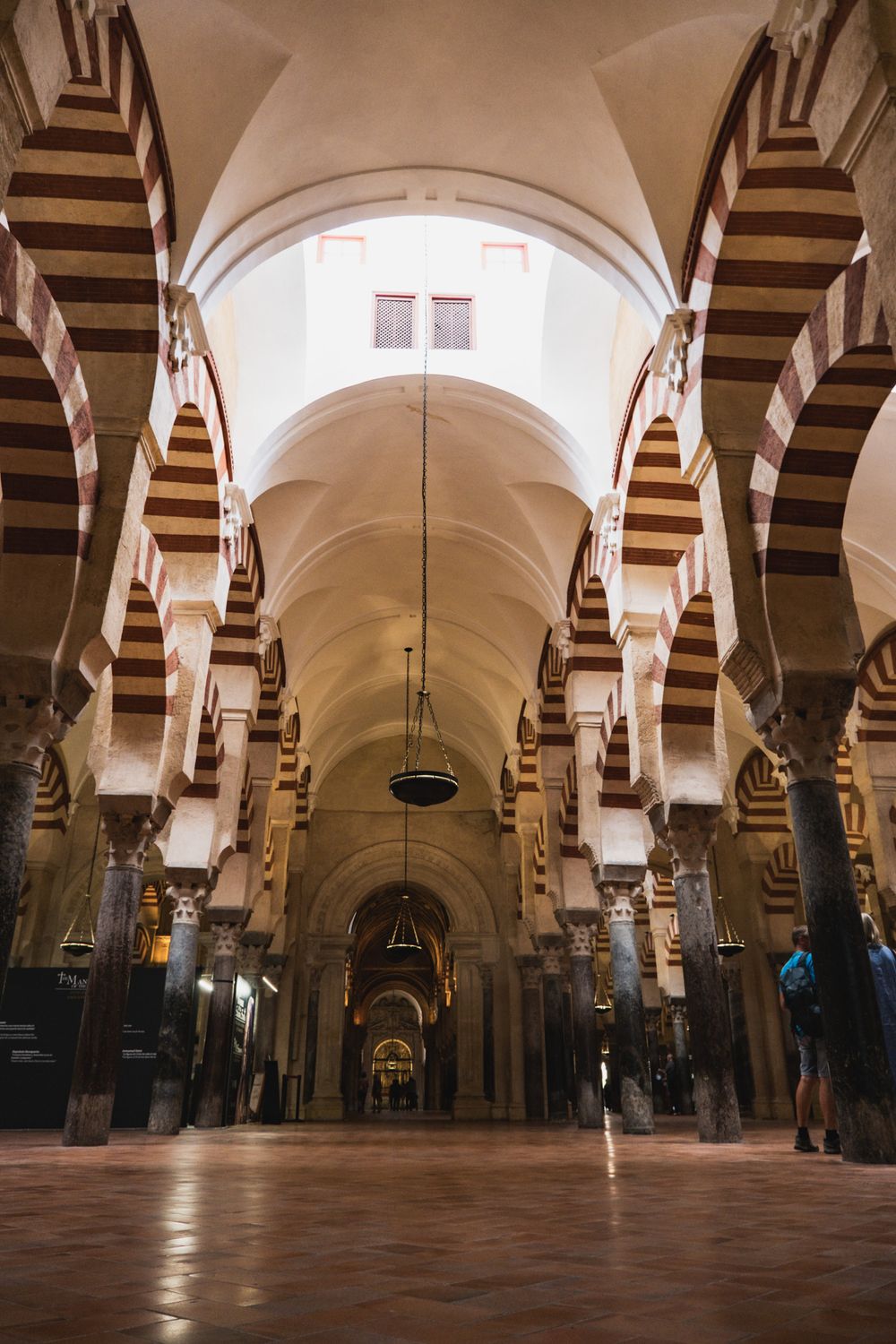 Interior of Mezquita-Catedral de Córdoba featuring iconic red and white striped arches and ornate columns.