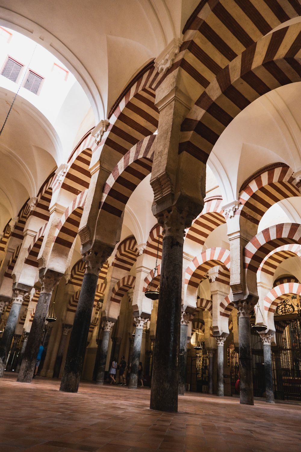 Interior of Mezquita-Catedral de Córdoba featuring iconic red and white striped arches and ornate columns.