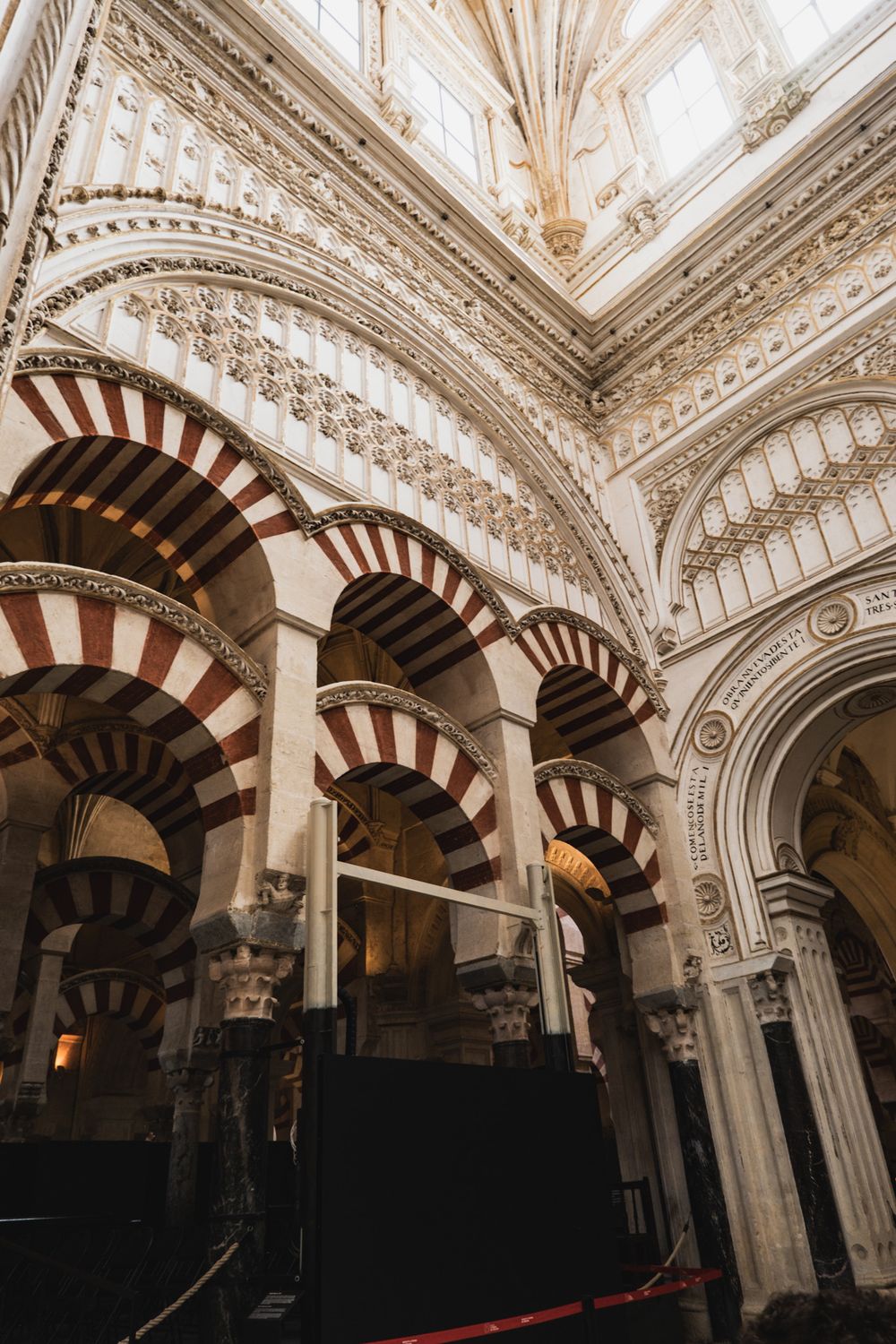 Interior of Mezquita-Catedral de Córdoba featuring iconic red and white striped arches and ornate columns.