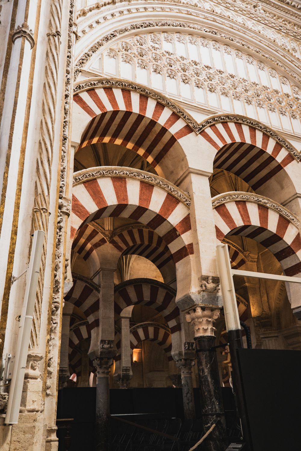 Interior of Mezquita-Catedral de Córdoba featuring iconic red and white striped arches and ornate columns.