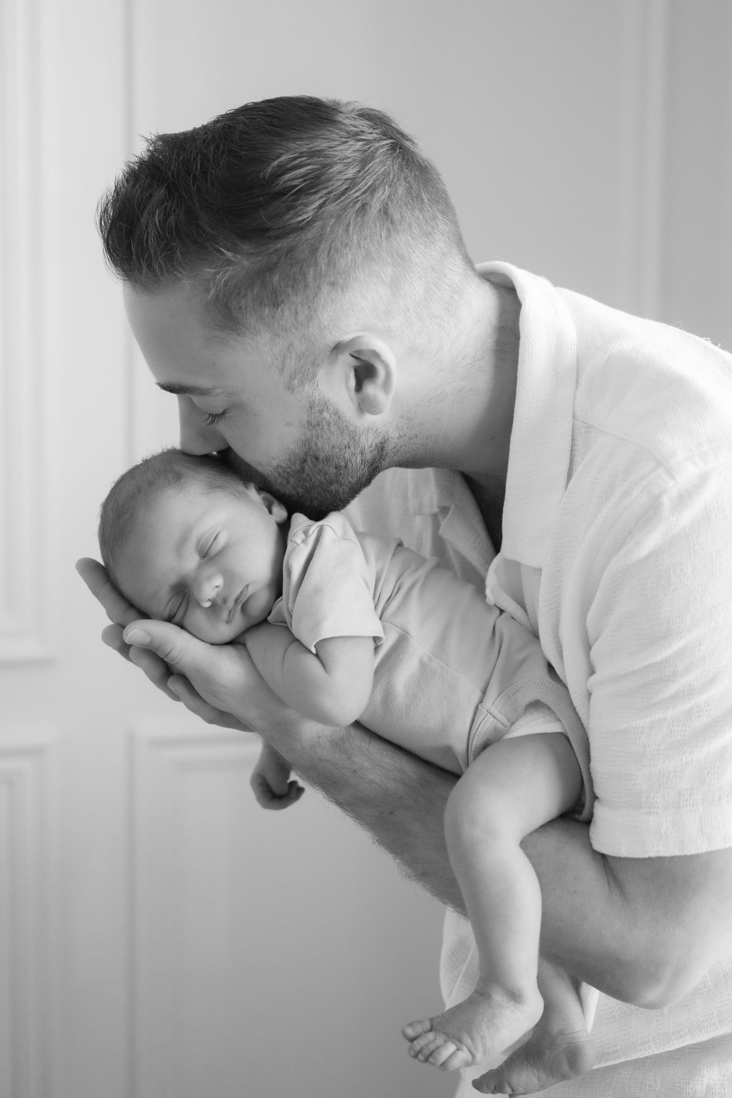 dad kissing and holding newborn baby in arms during in home lifestyle newborn session in hudson, wi