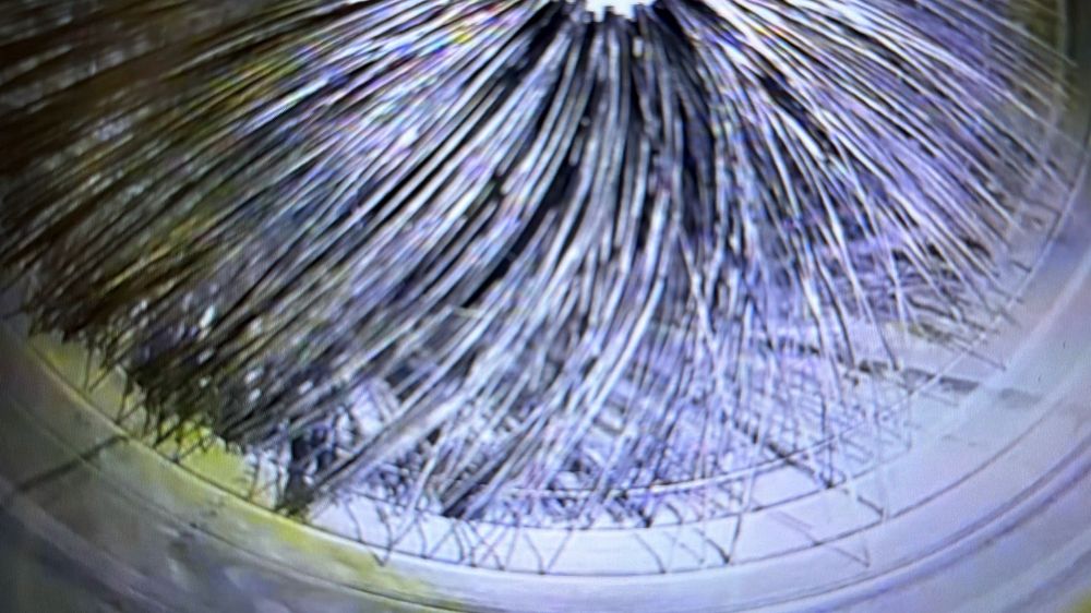 Close-up of radiating metallic fibers fanning outward in a circular pattern with intricate geometric lines.