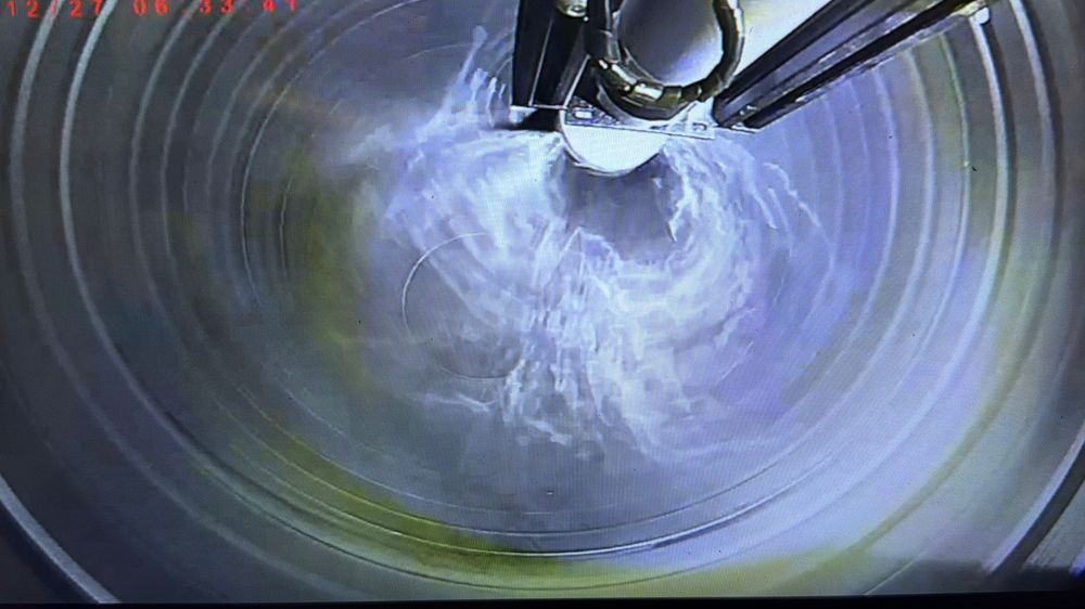 Close-up view inside a cylindrical pipe with water swirling, captured by an industrial pipe inspection camera.