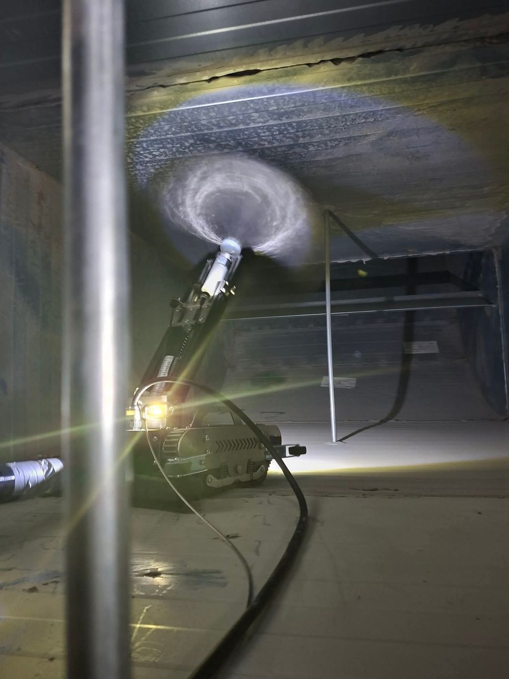 Professional air duct cleaning equipment in action, with rotating brush inside HVAC ductwork during maintenance service.