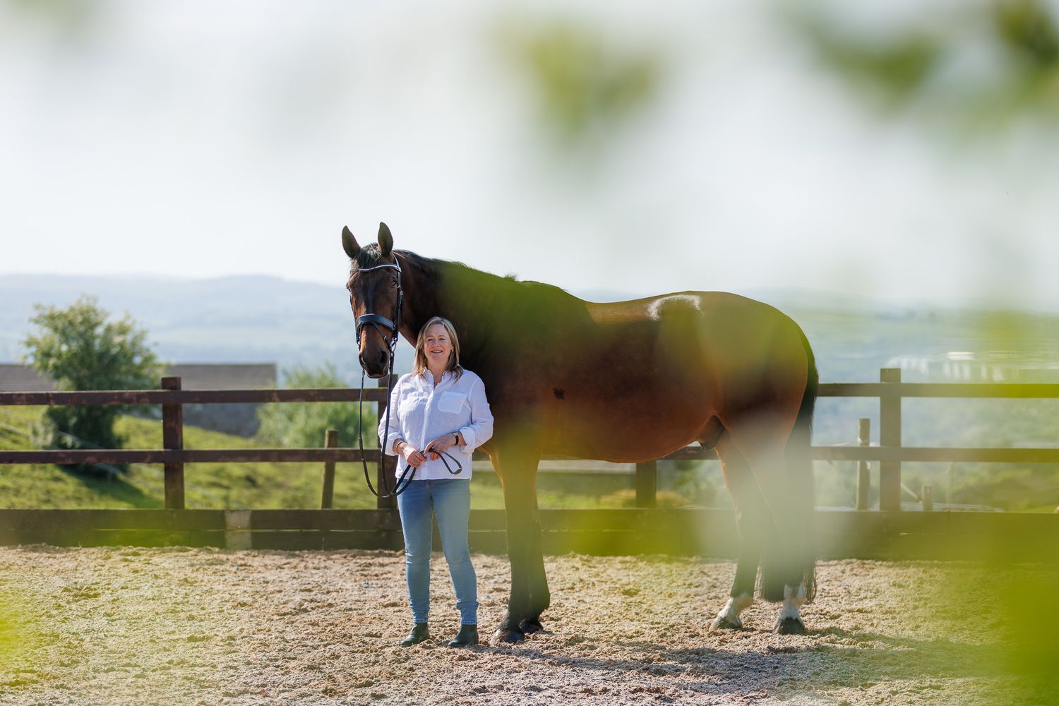 A horse and its rider enjoy an outdoor photoshoot session near rustic wooden fencing on a sunny day.