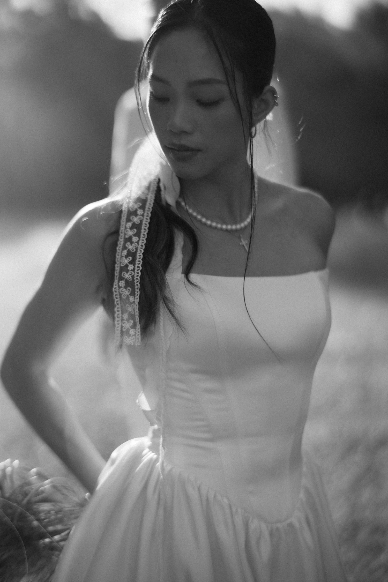 Black and white portrait of bride in strapless gown with pearl necklace in soft light.