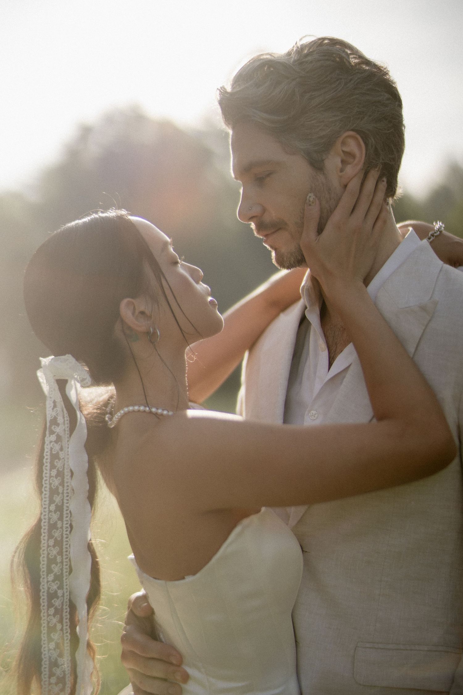 Bride and groom sharing a romantic almost-kiss moment in golden outdoor light.