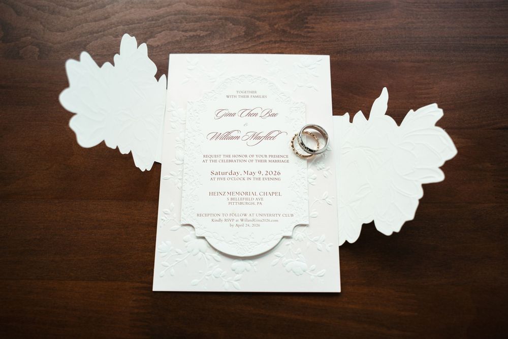 Wedding invitation with wedding rings arranged on a wooden table.