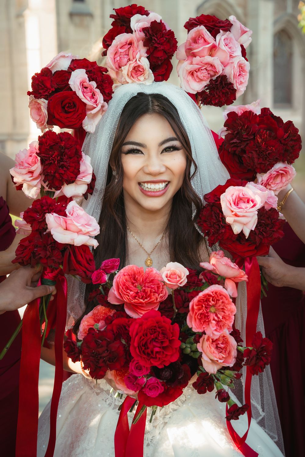 Bride smiling surrounded by her bridesmaid's bouquets during a creative bridal portrait.