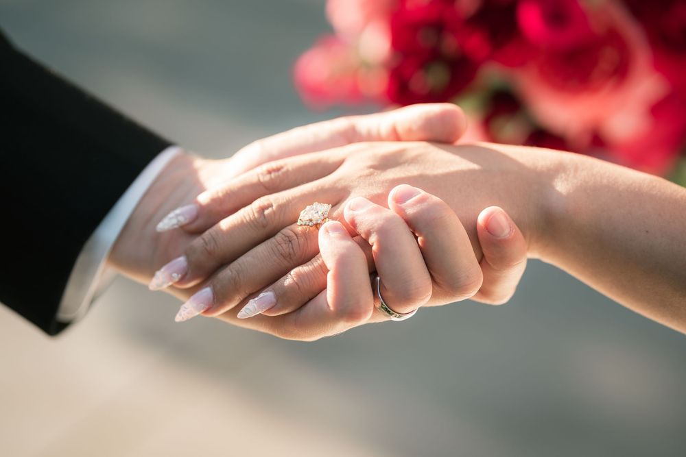 Close-up of bride and groom holding hands.