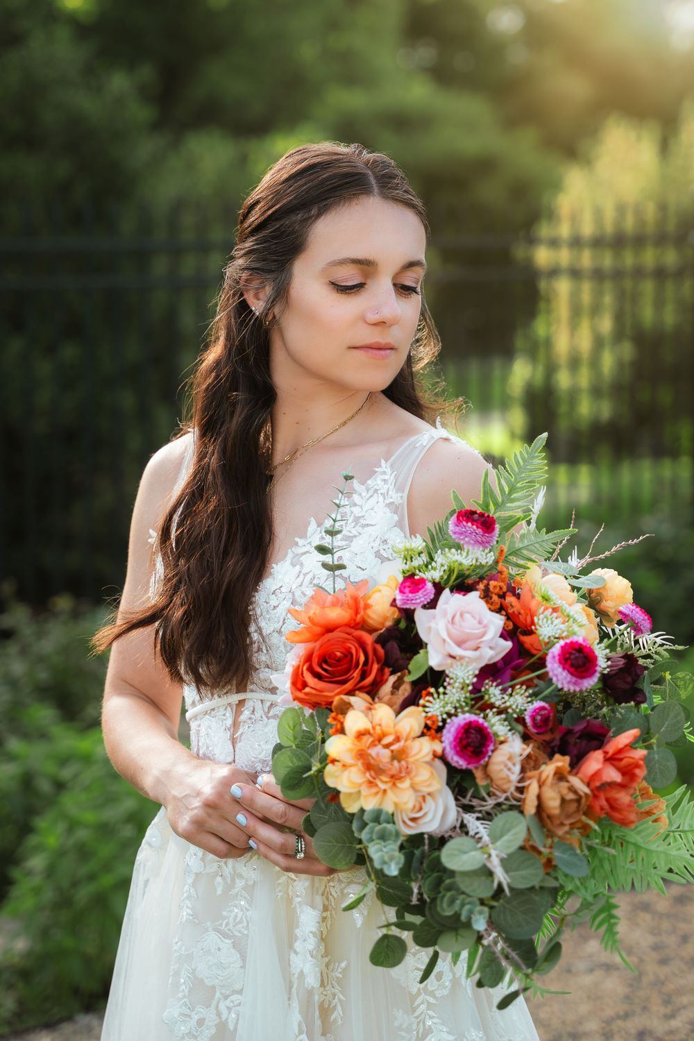 Bride admiring her colorful wedding bouquet during golden hour bridal portraits.