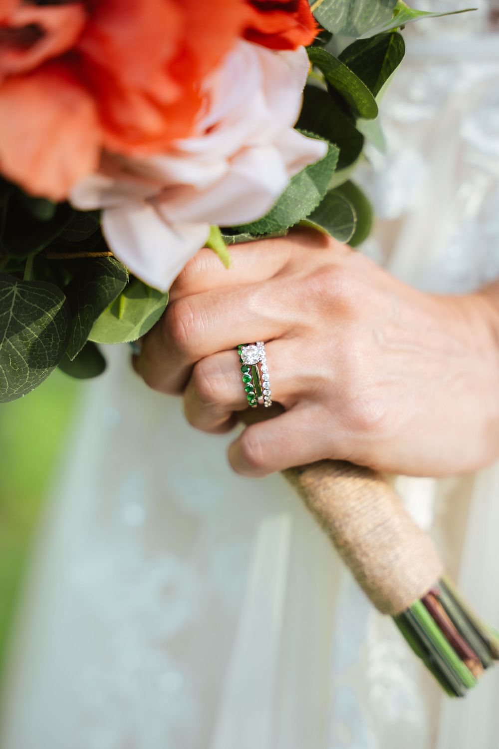 Bride holding her wedding bouquet with rings in focus.