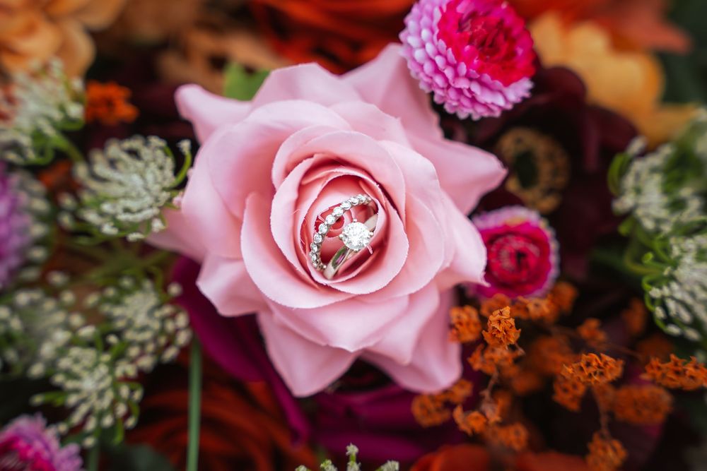 Close-up of a wedding ring nestled inside a pink rose bouquet.