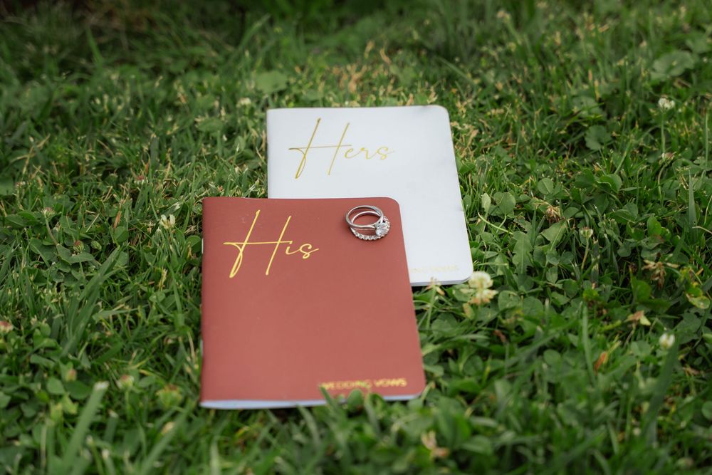 Wedding vow books resting on the grass before an outdoor ceremony.