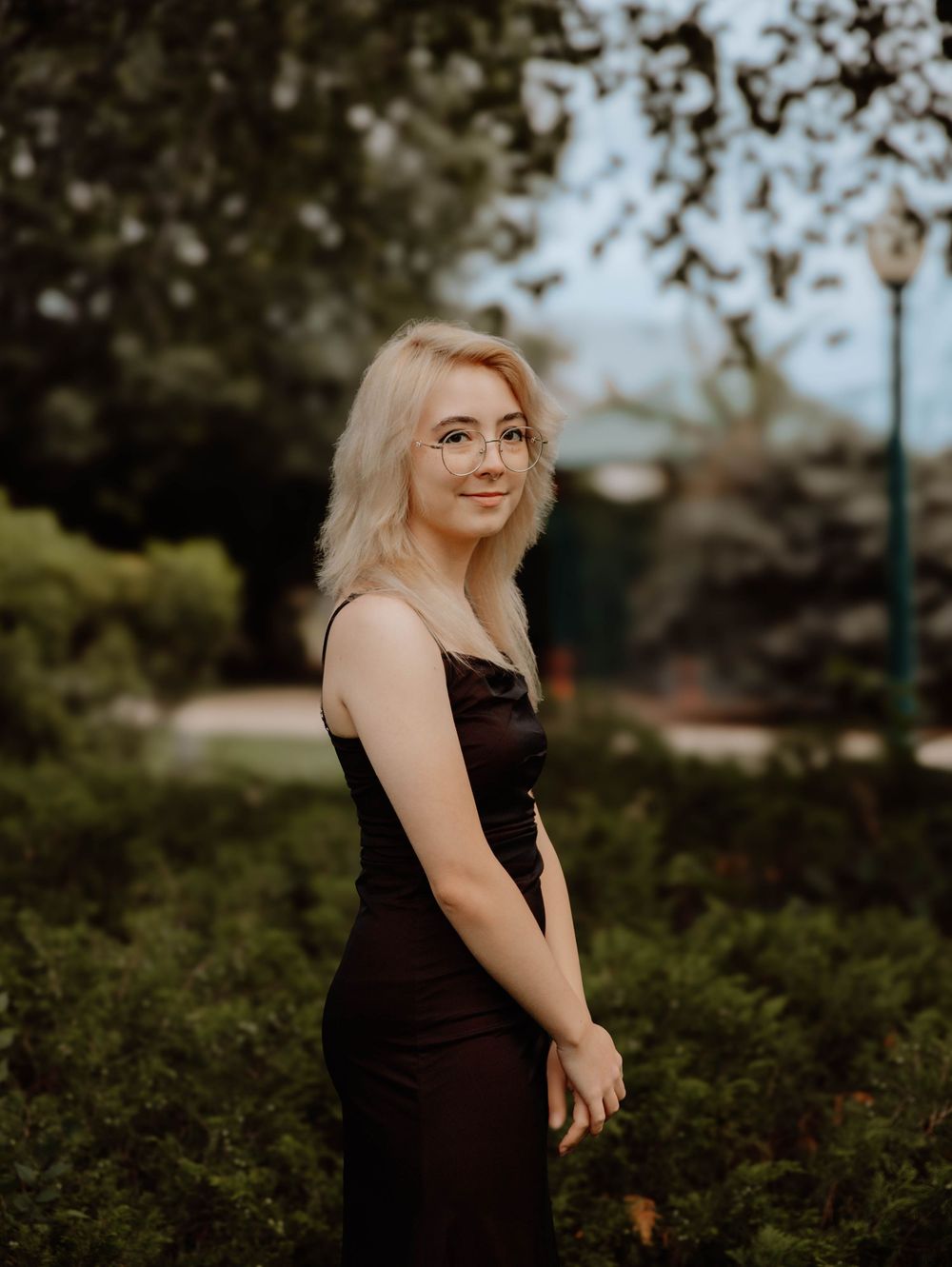 Girl stands and poses for senior photos in an urban town, cinematic photos, and portraits in Arvada, Colorado outside and in nature photo