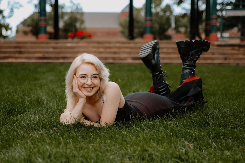 Girl poses laying down and happy for senior photos, cinematic photos, and portraits in Arvada, Colorado outside and in nature photo