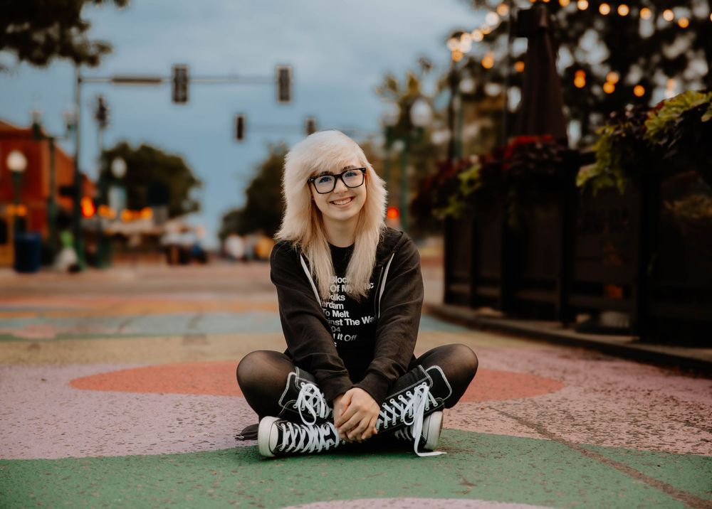 Girl sits down and poses for senior photos, cinematic photos, and portraits in Arvada, Colorado outside and in nature photo