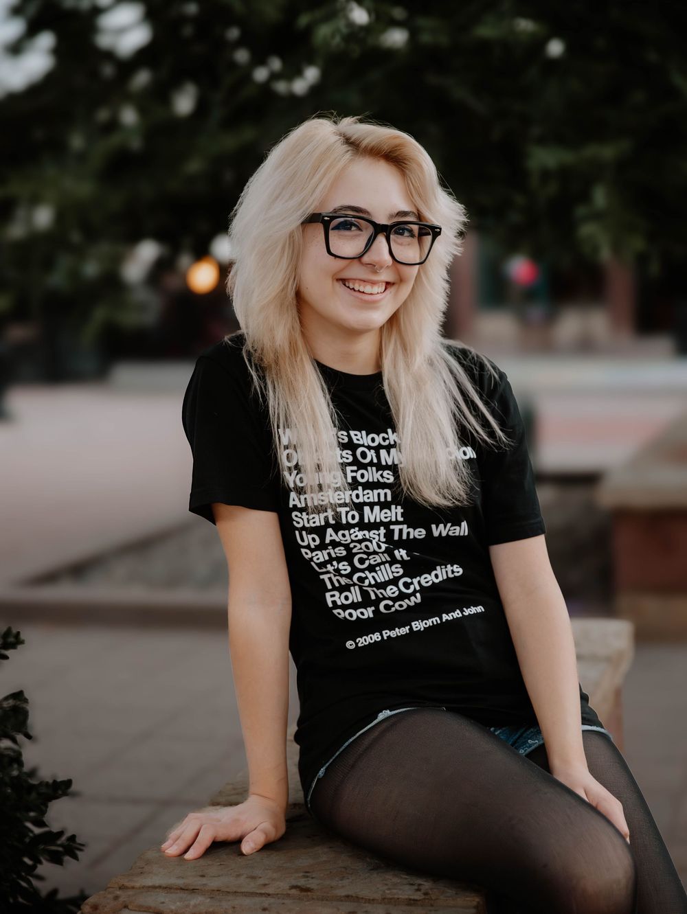 Girl sits down and poses for senior photos, cinematic photos, and portraits in Arvada, Colorado outside and in nature photo