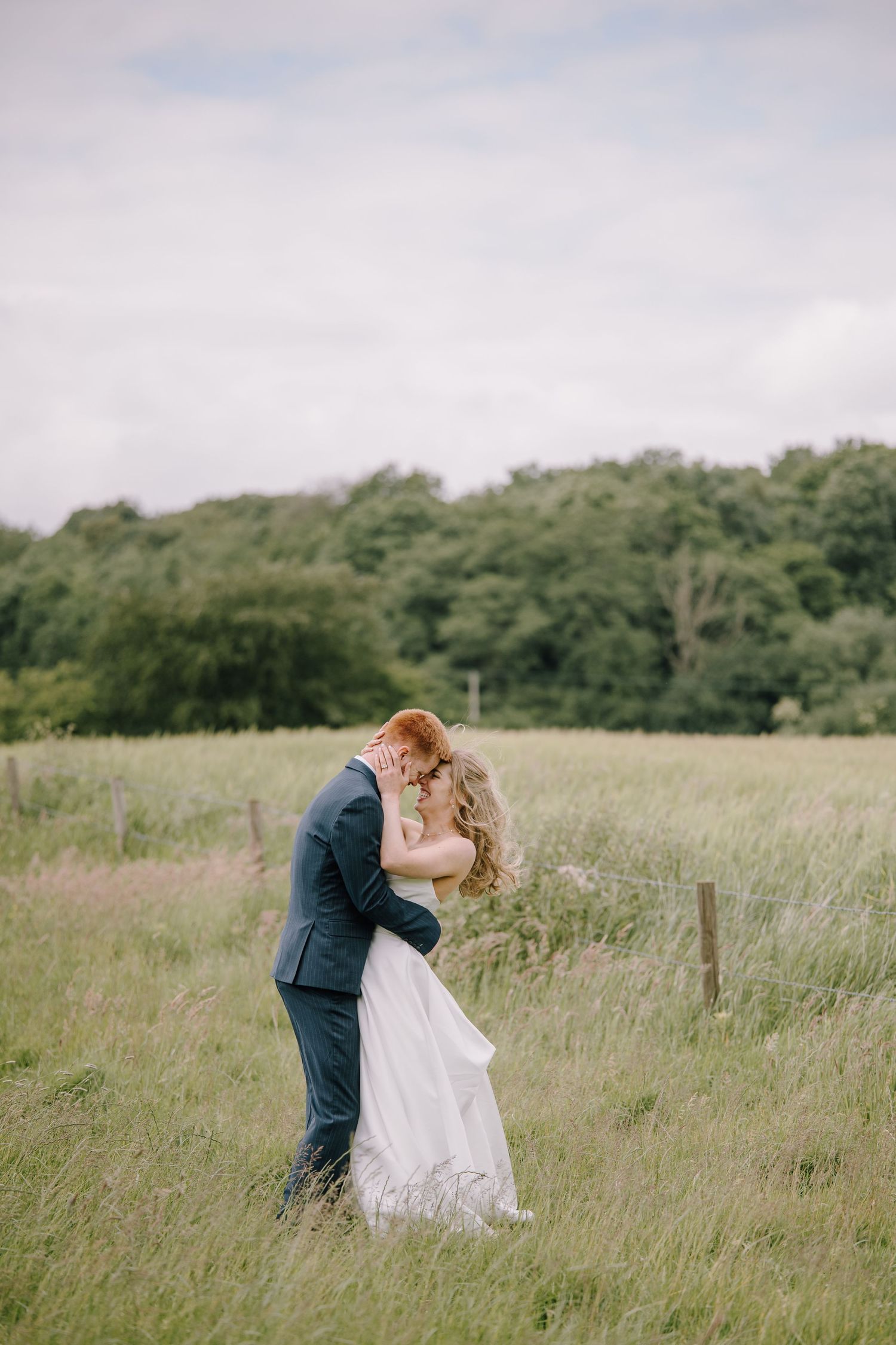 Bride and groom holding hands, showcasing diamond engagement ring, bride holding champagne glass in white wedding dress.