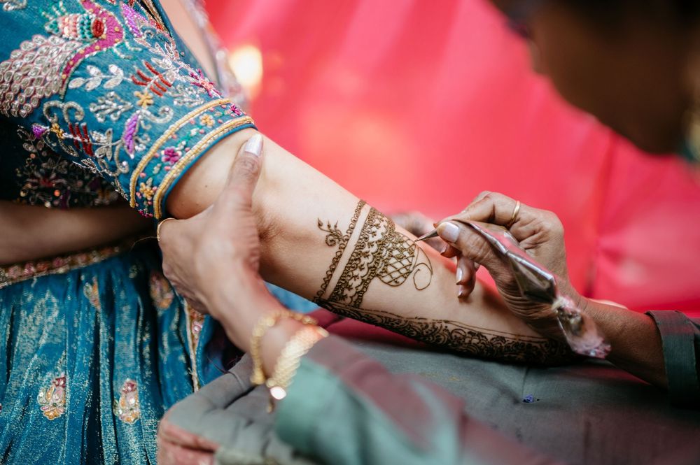 Artist applying intricate henna mehndi design on a bride's hand during traditional Indian wedding ceremony.