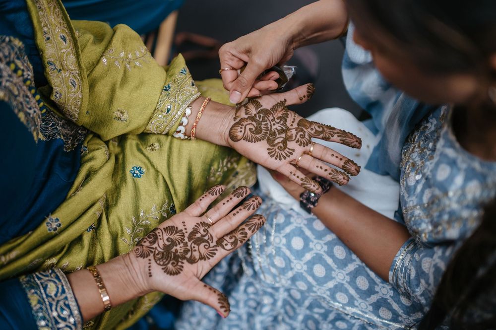 Close-up of intricate henna mehndi designs on hands during a traditional South Asian wedding ceremony.
