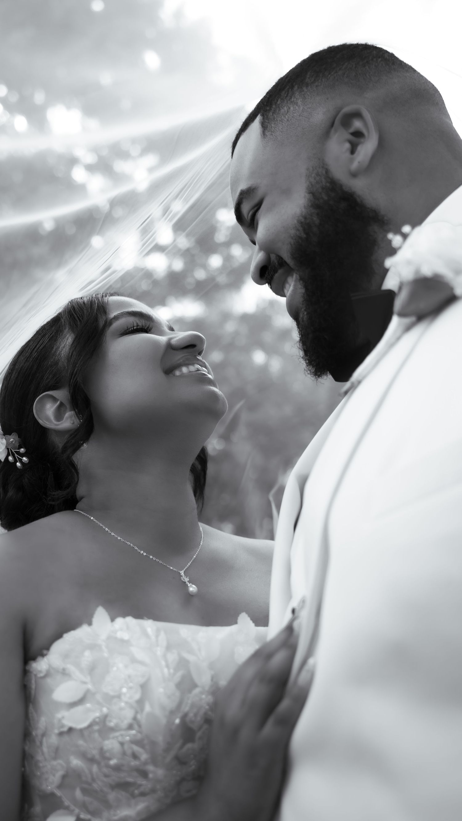 Black and white wedding photo of bride and groom sharing an intimate moment under a veil.