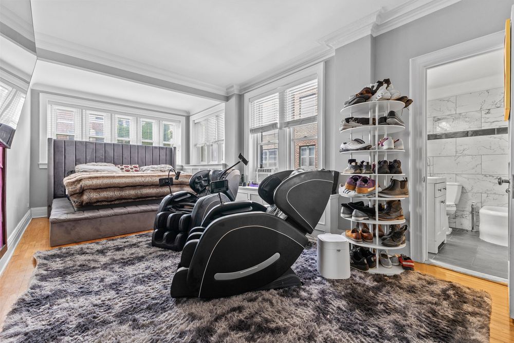 Bright living room with massage chairs, shoe rack, hardwood floors, and large windows.