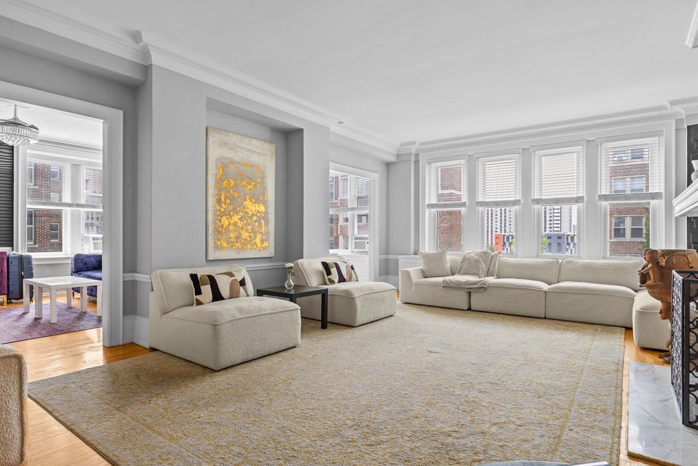 Bright luxury condo living room with large windows overlooking Detroit's East Jefferson waterfront district.