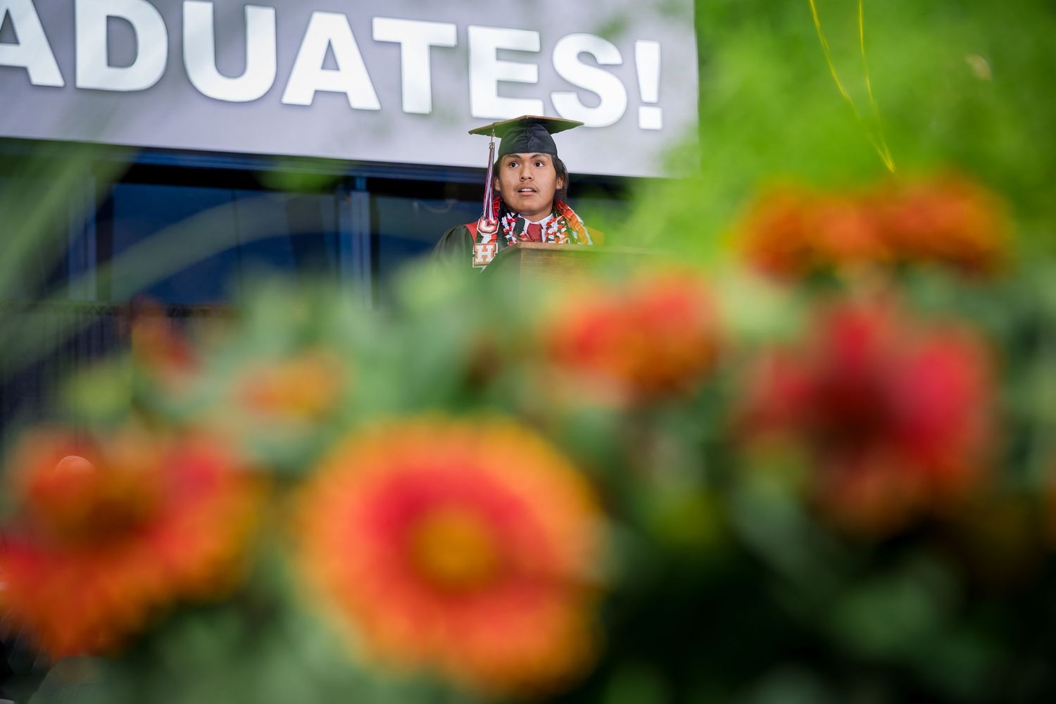 Elena Klopfenstein, standing at a podium, welcomed the 2025 CHS Graduation crowd in Navajo.