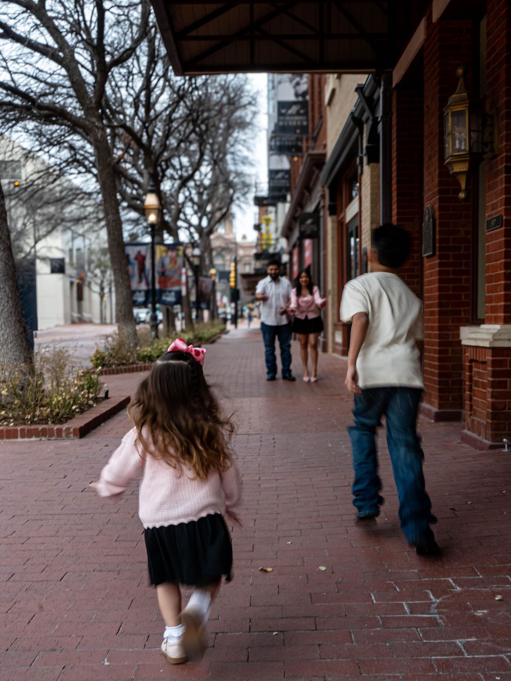 Children and family walking along brick sidewalk in charming downtown shopping district.