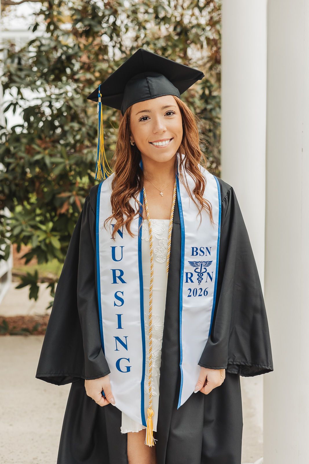 Nursing graduate smiling in black cap and gown with BSN RN 2026 stole at graduation ceremony.