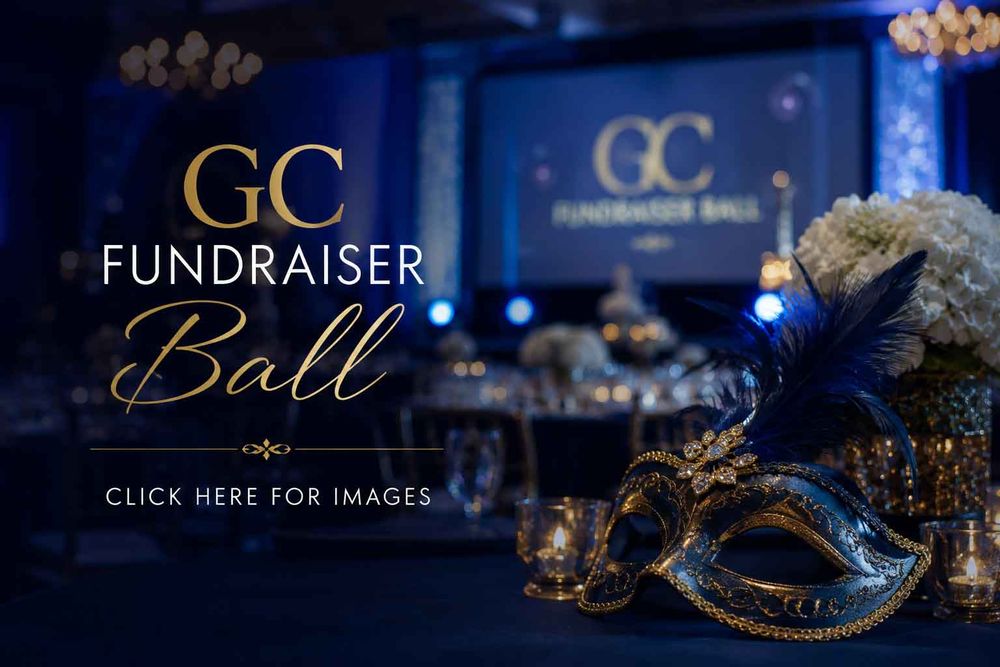 Elegant GC Fundraiser Ball event with a masquerade mask, blue feathers, and floral decor in a luxurious ballroom setting.