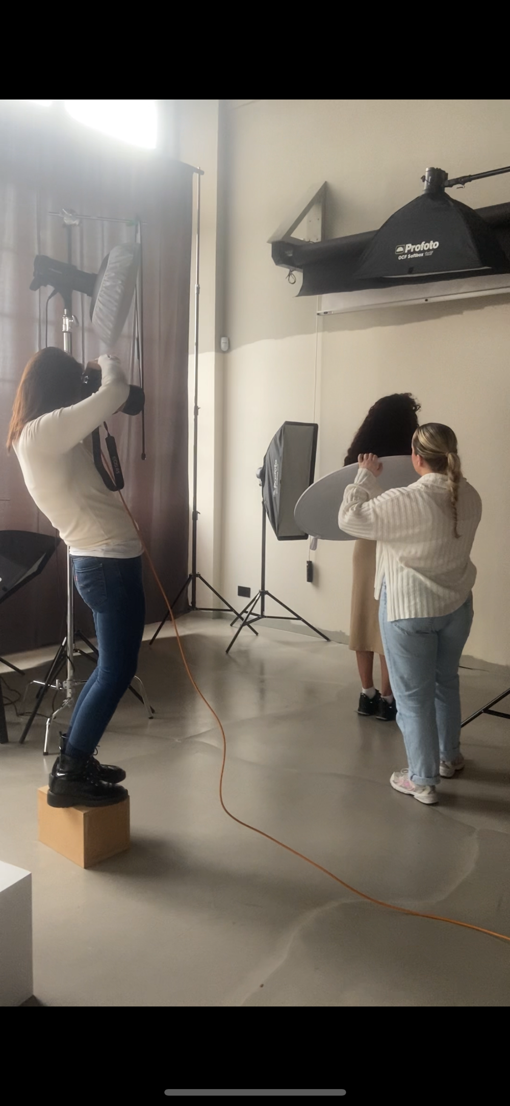 Two photographers working in a professional studio with Profoto lighting equipment during a photo shoot.