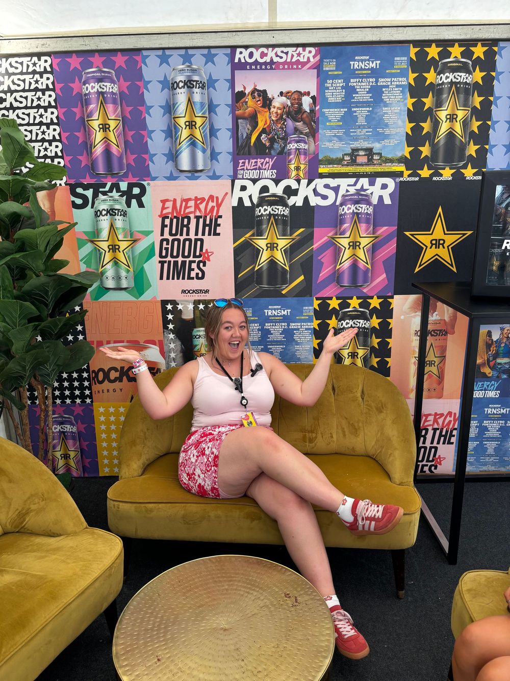 Woman posing on sofa in front of Rockstar Energy drink display.