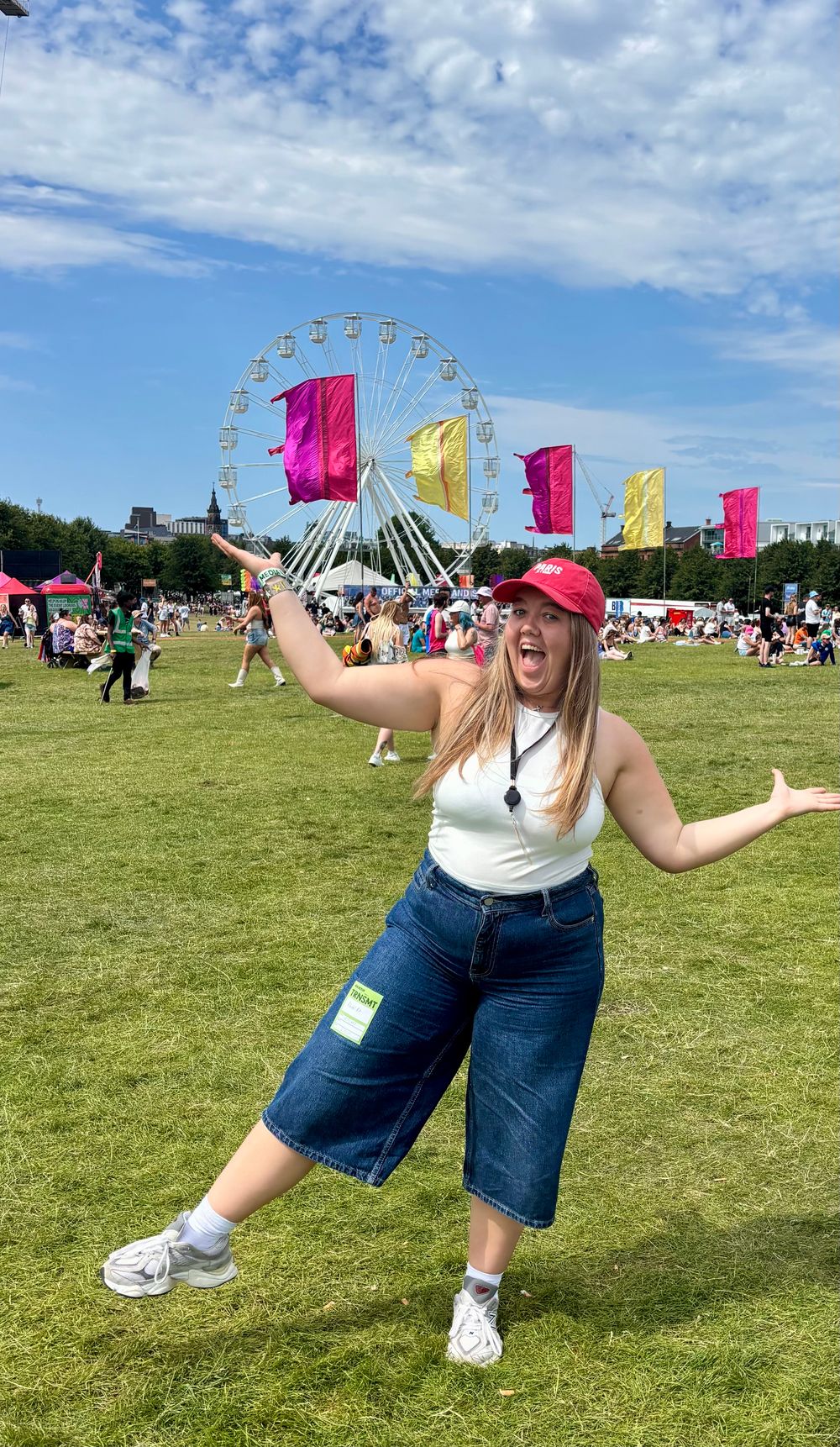 Woman posing at outdoor festival with Ferris wheel behind her.