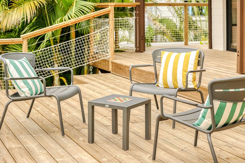 Gray metal outdoor chairs with striped cushions surrounding a small side table on a wooden deck patio.