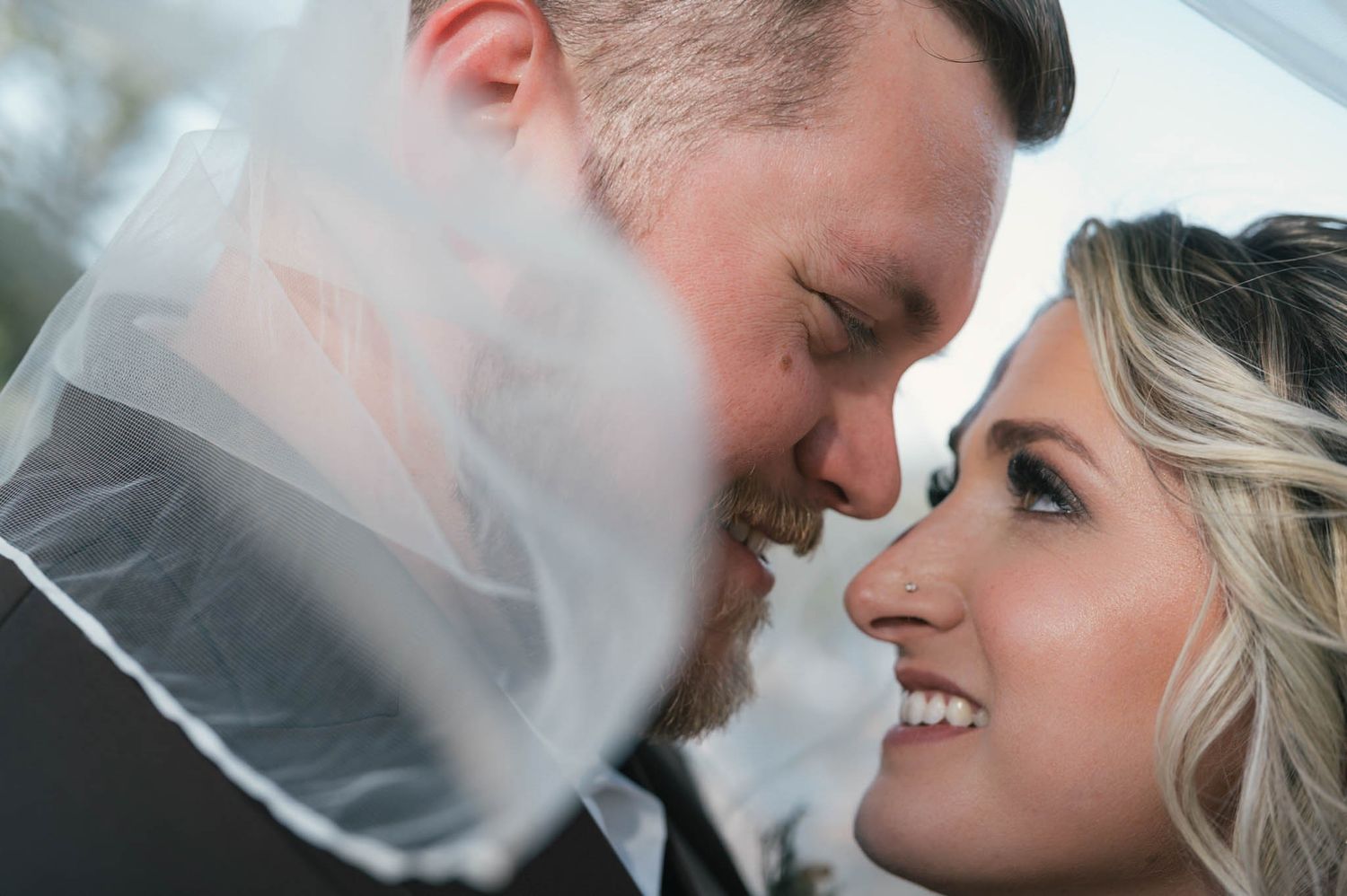 Bride and groom sharing an intimate moment under a veil during their wedding photo session.