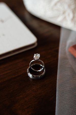 Three stacked wedding rings including diamond engagement ring displayed on a dark wooden surface.