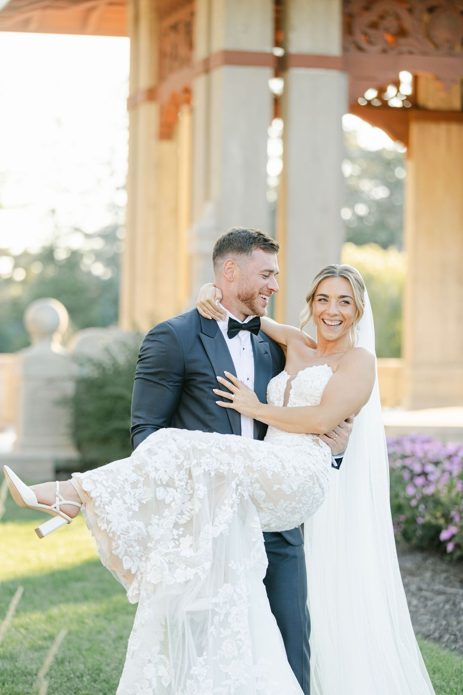 Armour House Wedding - Groom in navy tuxedo with black bow tie buttoning jacket outdoors at elegant wedding venue.