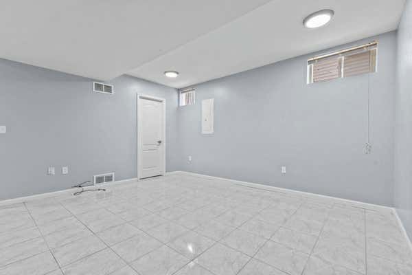 Bright basement room with white tile floors, light gray walls, and small windows.