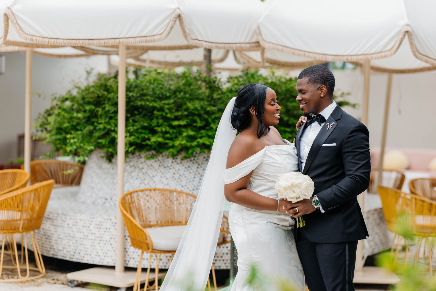 Romantic outdoor wedding ceremony with palm trees and flowing white veil.