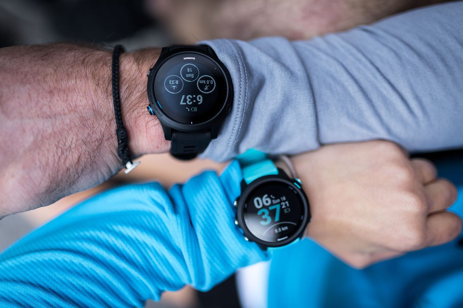 Two smartwatches displayed on wrists, showing fitness tracking data on their digital screens.