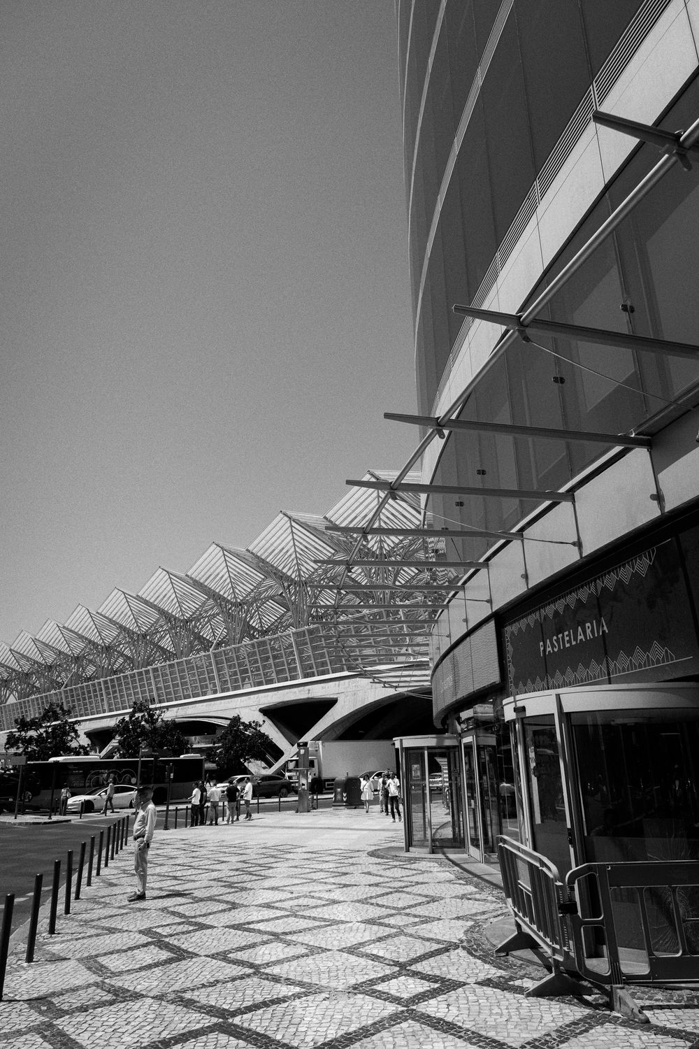 Black and white photo of modern architectural train station Lisbon Orient Station, with sweeping canopy roof and geometric steel structure.