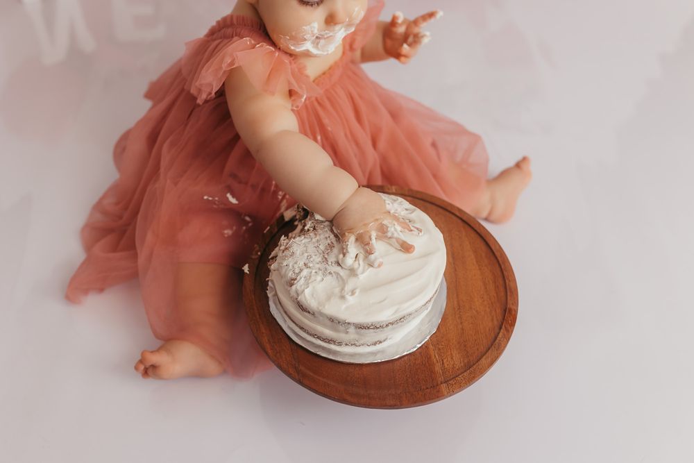 Detail photo of babys hand in her first birthday cake during cake smash photos.