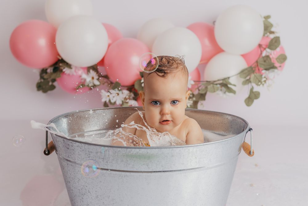 Toddler splashing in the tub to get washed up after he cake smash session in Weston, WI