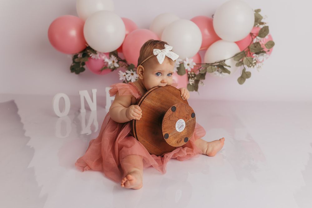 Baby girl eating the cake stand before getting her cake in her studio photos.