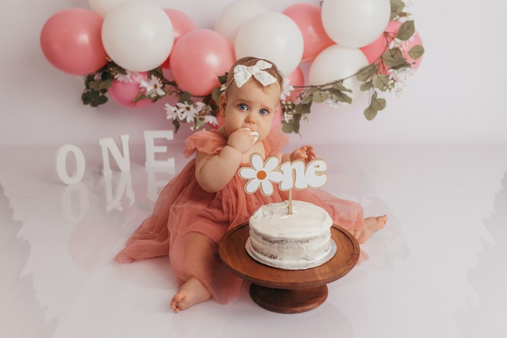 Toddler eating her cake during her cake smash one year photos.